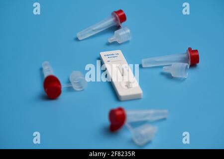 Antigen-Test auch Corona-Schnelltest mit Testkassette und Probenröhrchen auf einer blauen Oberfläche. Konzentrieren Sie sich auf die blauen Covid-19-Buchstaben. Nahaufnahme. Stockfoto