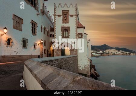 Mittelalterliche Gebäude in Sitges, Katalonien, Spanien mit sanftem Sonnenuntergang am Himmel in der Abenddämmerung Stockfoto