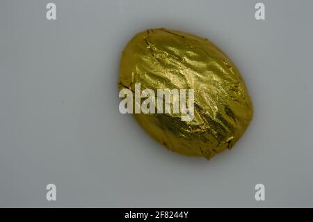 Schokolade in goldener Verpackung auf grauem Hintergrund. Isoliert. Speicherplatz kopieren. Stockfoto