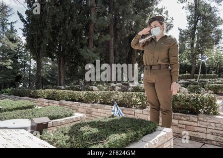 Jerusalem, Israel. April 2021. IDF-Soldaten legen kleine israelische Fahnen mit schwarzen Bändern auf jedes der Gräber und grüßen die Gefallenen auf dem Militärfriedhof von Mount Herzl vor dem Gedenktag, Jom Hazikaron, für die gefallenen Soldaten und Opfer von Terroranschlägen. Der Gedenktag wird am 14. April 2021 markiert. Kredit: Nir Alon/Alamy Live Nachrichten Stockfoto