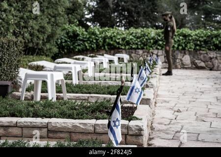 Jerusalem, Israel. April 2021. IDF-Soldaten legen kleine israelische Fahnen mit schwarzen Bändern auf jedes der Gräber und grüßen die Gefallenen auf dem Militärfriedhof von Mount Herzl vor dem Gedenktag, Jom Hazikaron, für die gefallenen Soldaten und Opfer von Terroranschlägen. Der Gedenktag wird am 14. April 2021 markiert. Kredit: Nir Alon/Alamy Live Nachrichten Stockfoto