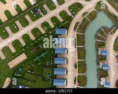 Henlow Bridge Lakes, Bedfordshire, Großbritannien. April 2021. Leere Campingfelder und Hütten im Schweizer Stil sind für ihre ersten Besucher seit dem Lockdown bereit. In sich geschlossene Camper mit Reisemobilen und Wohnwagen dürfen ab Montag, dem 12. April 2021, in England übernachten.die Lodges und Hütten sind in sich geschlossen und werden auf hohem Niveau gereinigt und vor der Ankunft beschlagen. Die Campingplätze müssen den staatlichen Vorschriften entsprechen, damit der Waschraum und die Toiletten des Campingplatzes erst am 17. Mai 2021 vollständig geöffnet werden können. Kredit: Mick Flynn/Alamy Live Nachrichten Stockfoto