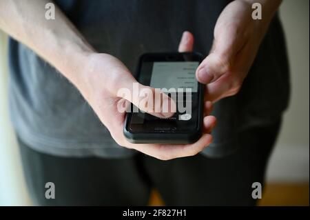 Nahaufnahme eines jungen Mannes, der auf seinem Mobiltelefon auf die Uber-App zugreift. Stockfoto