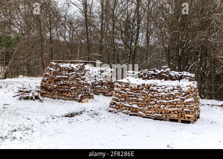 Holzstapel. Verschneite Feuerhölzer im Winterwald in Tschechien. Ökologische Heizung. Holzlager. Stockfoto