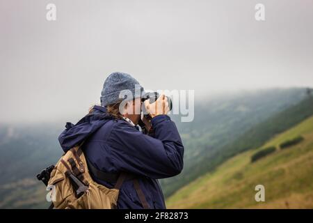 Wanderer mit Kamera fotografiert die Landschaft beim Wandern in den Bergen. Abenteuer in der Natur Stockfoto