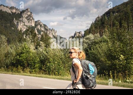 Reisende wandern auf der Straße in den Bergen im Naturpark Mala Fatra, Slowakei. Reise- und Active Lifestyle-Konzept. Frau mit Rucksack während des Sommerurlaubes Stockfoto