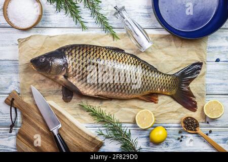 Fisch kochen. Frischer Karpfen und Zutaten auf weißem Tisch. Gesunde Ernährung vorbereiten. Flach liegend Stockfoto