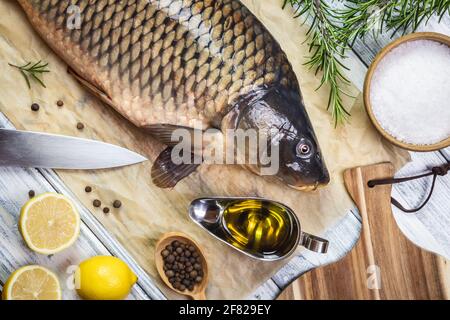 Zubereitung und Kochen von gesunden Lebensmitteln. Karpfenfisch, Kräuterwürze und Zutaten auf dem Tisch Stockfoto