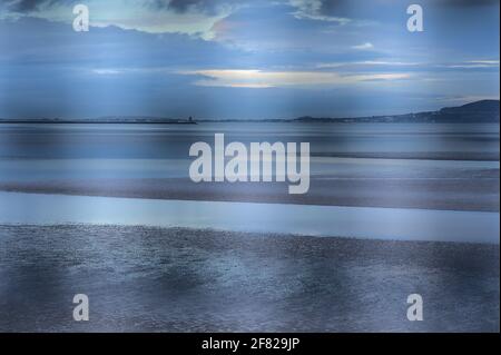 Wunderschöne Abendansicht von Blackrock Beach bei Ebbe vom Bahnhof aus durch den Metallzaun, Dublin Irland. Kreative Unschärfe Stockfoto