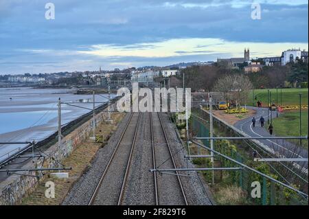 Dublin, Irland - 14. März 2021: Wunderschöne, am Abend kontrastierende, nach Süden ausgerichtete Ansicht der irischen Eisenbahn entlang der Küste von Dublin, gesehen bei Blackrock Stockfoto