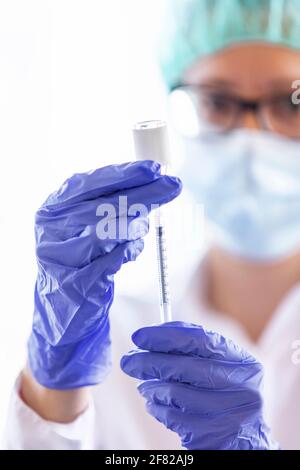Der Arzt füllt eine Spritze mit Impfstoff auf verschwommenem Hintergrund. Stockfoto