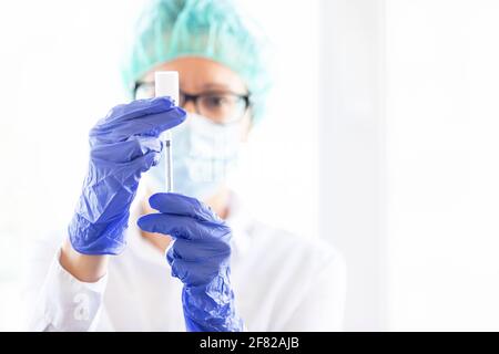 Der Arzt füllt eine Spritze mit Impfstoff auf verschwommenem Hintergrund. Stockfoto