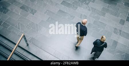 Draufsicht auf zwei Geschäftskollegen, die zusammen über den Flur des Büros laufen. Geschäftsleute kommen, um zusammenzuarbeiten. Stockfoto