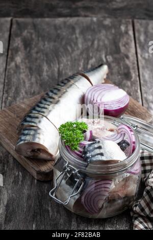 Makrelen in Salzlake mit Zwiebeln und Gewürzen im Glasgefäß Auf Holztisch Stockfoto