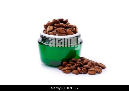 Grünes Gesichts-Creme-Glas mit Kaffeebohnen in ihm auf isoliert auf weißem Hintergrund. Natürliche pflanzliche Kosmetik Konzept, Stockfoto