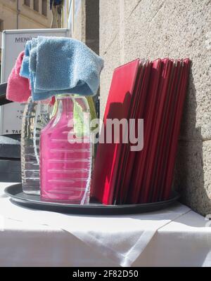 Kellnertablett mit Desinfektionsmittel-Spray-Produkten über der Restaurantterrasse. Covid-19 Messungen im Hostelry-Konzept Stockfoto
