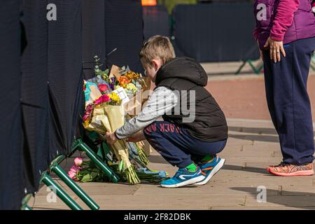 BUCKINGHAM PALACE LONDON, GROSSBRITANNIEN 11. APRIL 2021. Ein kleiner Junge bringt Blumen in den Buckingham Palace, um Prinz Philip, Herzog von Edinburgh, zu ehren, der im Alter von 99 Jahren starb. Ihre Majestät, die Königin, gab den Tod ihres Mannes, seiner königlichen Hoheit Prinz Philip, Herzog von Edinburgh, bekannt, der am 9. April in Windsor Castle Credit amer ghazzal/Alamy Live News friedlich verstarb Stockfoto