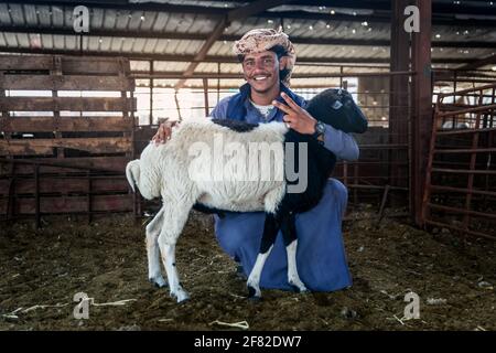 Dammam, Saudi-Arabien - 02-April-2021. Junger erwachsener Mann mit seiner Ziege auf ihrer Rinderfarm. Stockfoto