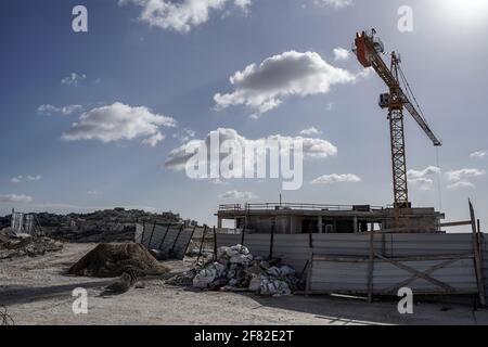 Jerusalem, Israel. April 2021. Der Bau in Homat Shmuel, oder Har Homa, in Ostjerusalem, mit dem palästinensischen Dorf Umm Tuba im linken Hintergrund, auf 1991 enteigneten Land, als ein Jerusalemer Komitee einen Plan für weitere 540 Wohneinheiten billigt. Das jüdische Viertel jenseits der Grünen Linie, die Abgrenzungslinie des Waffenstillstands vor dem Sechstagekrieg von 1967, der Israel und das Westjordanland trennt, wird von einem Großteil der Welt als illegale israelische Siedlung angesehen. Der Plan ist das erste große Bauprojekt über die Grenzen vor 1967 seit US-Präsident B Stockfoto