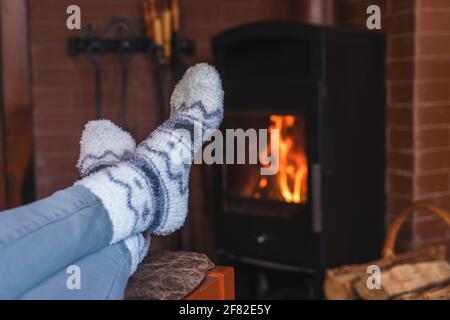 Frau sitzt in Wollsocken in der Nähe des Kamins. Entspannung in der Wintersaison an den weihnachtsferien. Stockfoto