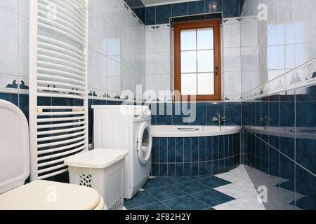 Badezimmer mit Badewanne und Waschmaschine in einem Flach mit Fliesen in Politur Stockfoto