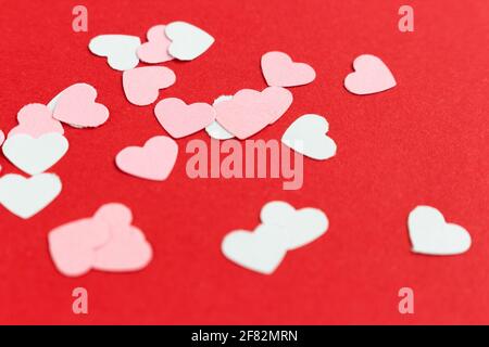 Viele bunte Papier herzförmige Konfetti auf rosa oder rotem Hintergrund. Valentinskarte. Stockfoto