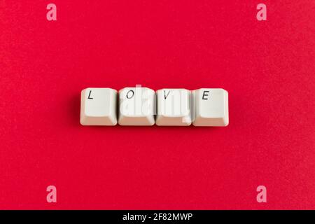 Computer-Tastatur-Tasten mit Liebeswort geschrieben mit den weißen Tasten auf rotem Hintergrund. Valentinskarte. Urlaubskonzept. Stockfoto