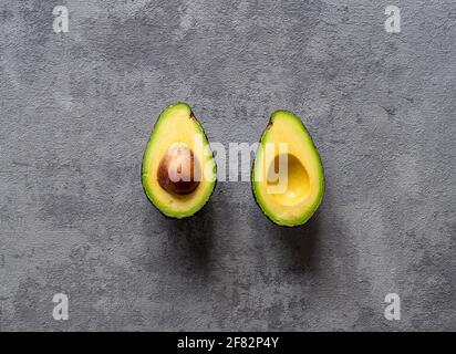 Eine kreative Draufsicht auf eine geschnittene Avocado auf texturierter Oberfläche Grauer Hintergrund Stockfoto
