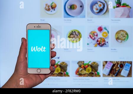 Wolt-Konzept für die Lebensmittelzustellung. Weibliche Hand hält vor dem Bildschirm Handy mit finnisches Firmenlogo und Webseite mit Plattform-Restaurant-Partnern Stockfoto