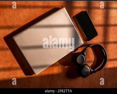 Büro zu Hause mit IT-Ausrüstung und Online-Kommunikation. Arbeiten von zu Hause aus und Fernzugriffskonzept. Selektiver Fokus und Sonnenlicht auf IT-Ausrüstung Stockfoto