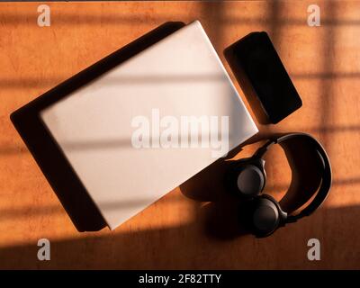 Büro zu Hause mit IT-Ausrüstung und Online-Kommunikation. Arbeiten von zu Hause aus und Fernzugriffskonzept. Selektiver Fokus und Sonnenlicht auf IT-Ausrüstung Stockfoto