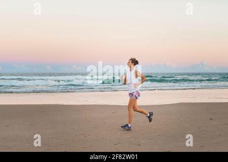 Junge schöne sportliche Frau macht Übungen am Strand Stockfoto