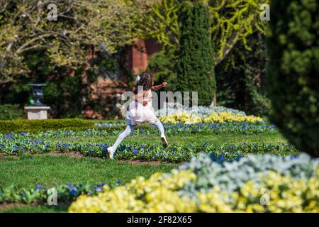 Ein junges afroamerikanisches Mädchen, das sich in ihrer Osterschönster verkleidet, durchläuft die Gärten des Smithsonian Castle in Washington, D.C. Stockfoto