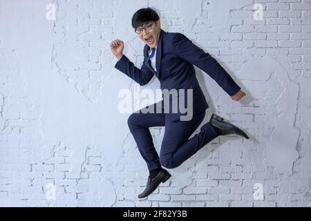 Lustige fröhliche Geschäftsmann springen in der Luft über weiße Wand Hintergrund Stockfoto