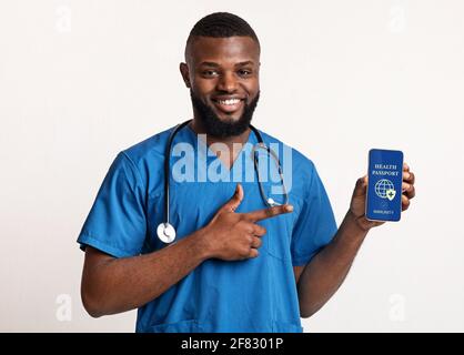 Schwarzer Arzt zeigt Smartphone mit immunem digitalen Pass für covid-19 Stockfoto