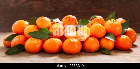 Frische Mandarinenorangen Früchte oder Mandarinen mit Blättern auf einem Holztisch Stockfoto