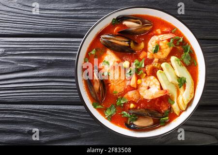 Köstliche Suppe mit Meeresfrüchten, Mais, Sellerie, Tomaten, Karotten und Avocado in einer Schüssel auf dem Tisch. Horizontale Draufsicht von oben Stockfoto