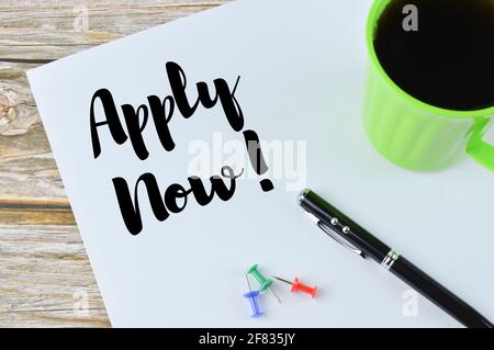 Draufsicht auf Stift, eine Tasse Kaffee und Pinnwände über weißem Papier geschrieben mit JETZT BEWERBEN! Stockfoto