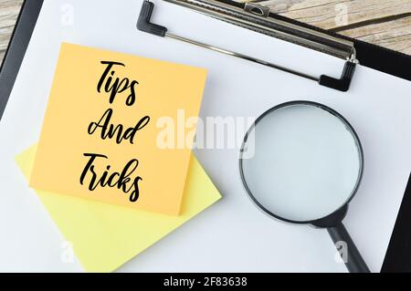 Draufsicht auf Lupe und Memonotiz geschrieben mit TEXTTIPPS UND -TRICKS Stockfoto