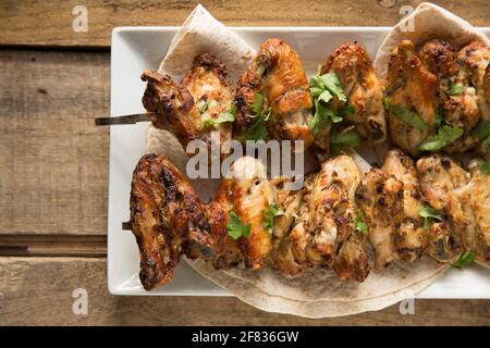 Britische Hähnchenflügel, die in Ras el Hanout marokkanischen Gewürzen mariniert wurden, bevor sie zu Hause Spieße und gegrillt wurden. England GB Stockfoto