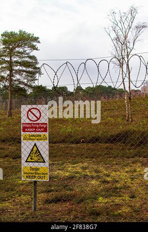 Gefahr, halten Sie Warnschild hinter einem Stacheldrahtzaun zum Schutz des Verteidigungsministeriums Land. Mit Kopierbereich Stockfoto