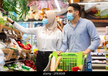 Muslim-Paar, Das Lebensmittel Einkaufen Trägt Gesichtsmasken Im Supermarkt Stockfoto