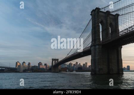 Hohe Hängebrücke aus Stein über Wasser im Sommer Mit hohen Gebäuden auf der anderen Seite bei Sonnenuntergang Stockfoto