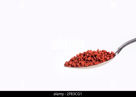 Achiote Samen im Löffel - Bixa orellana. Weißer Hintergrund Stockfoto