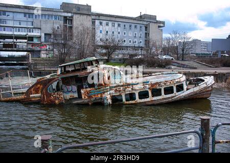 Altes rostig versunkenes Schiff im Wasser auf dem Territorium des Flusshafens. Altes versunkenes Boot auf dem Fluss. Stockfoto