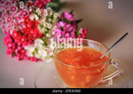 Tasse Getränk aus Ingwer und Honig auf dem Tisch mit Blumenhintergrund Stockfoto