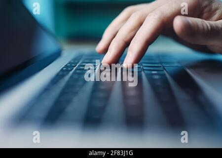 Selektive Fokuseingabe auf der Computertastatur. Finger einer Person während der Nutzung des Laptops in der Nacht. Stockfoto