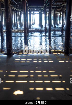 Blick auf unter einem Pier mit Sonnenlicht und Schatten Auf Sand Stockfoto