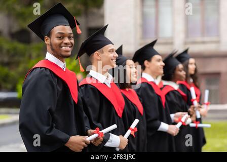 Diverse internationale Studenten mit Diplomen, die an der Abschlussfeier teilnehmen Stockfoto