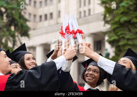 Glückliche multirassische Gruppe von Studenten, die Diplome ansammeln Stockfoto